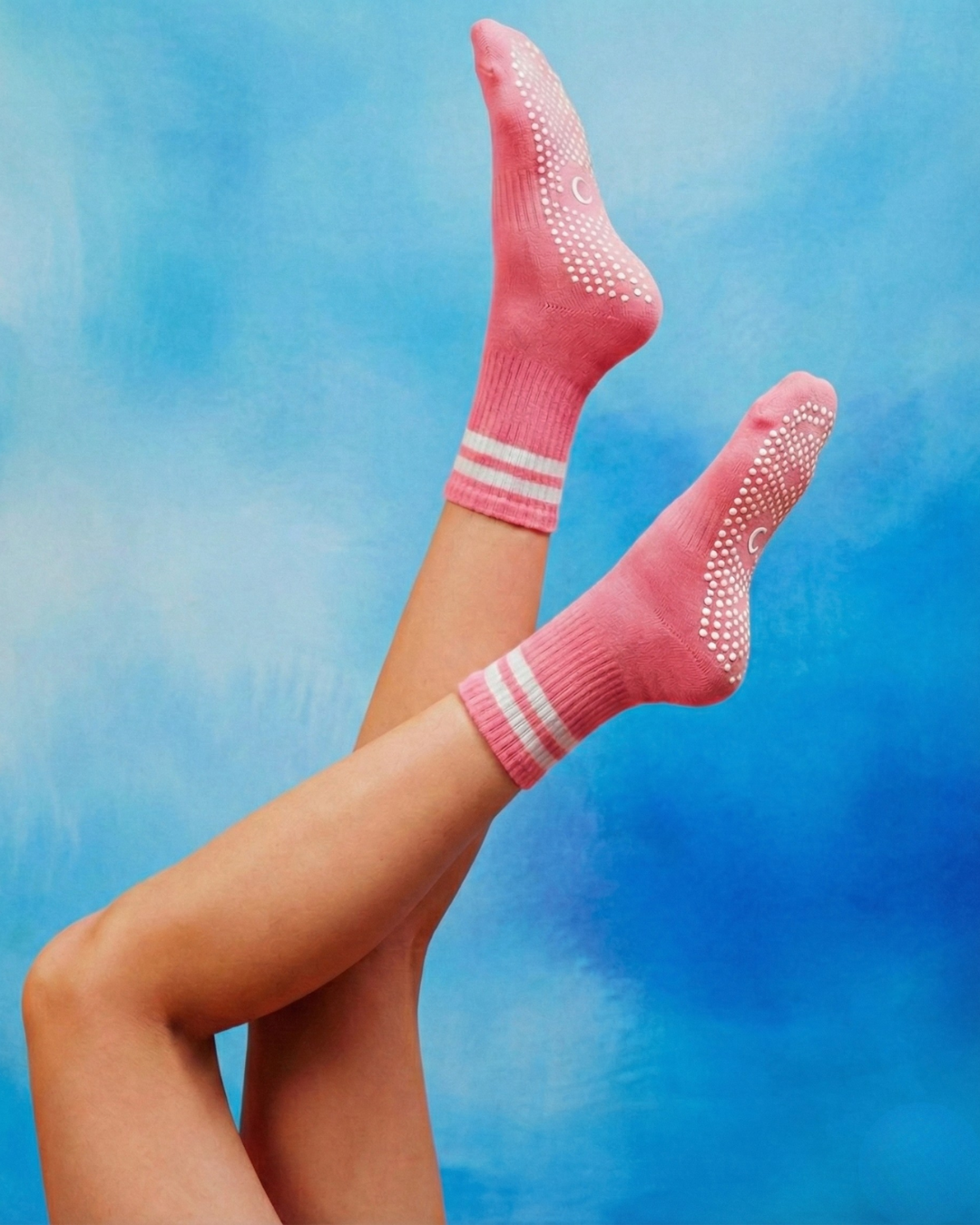 Rose pink pilates grip socks with white stripes centered logo.