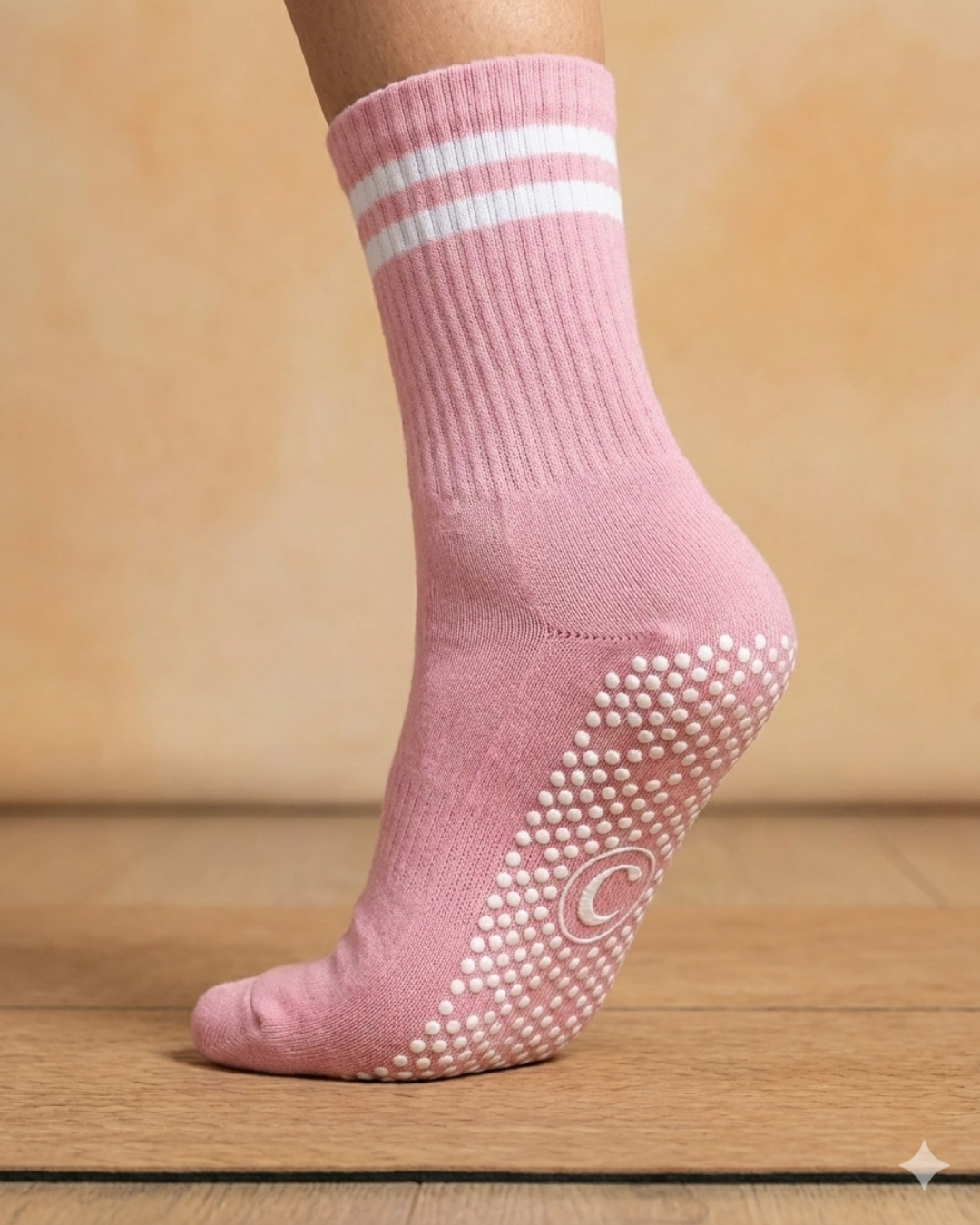 rose Pink pilates yoga grip sock with white stripes and textured sole on a wooden floor.